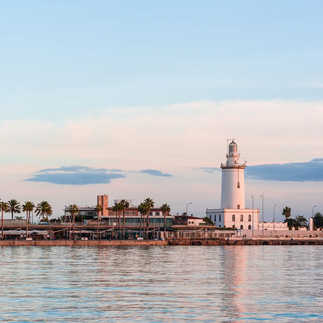 Malaga lighthouse and harbour against a clear blue sky