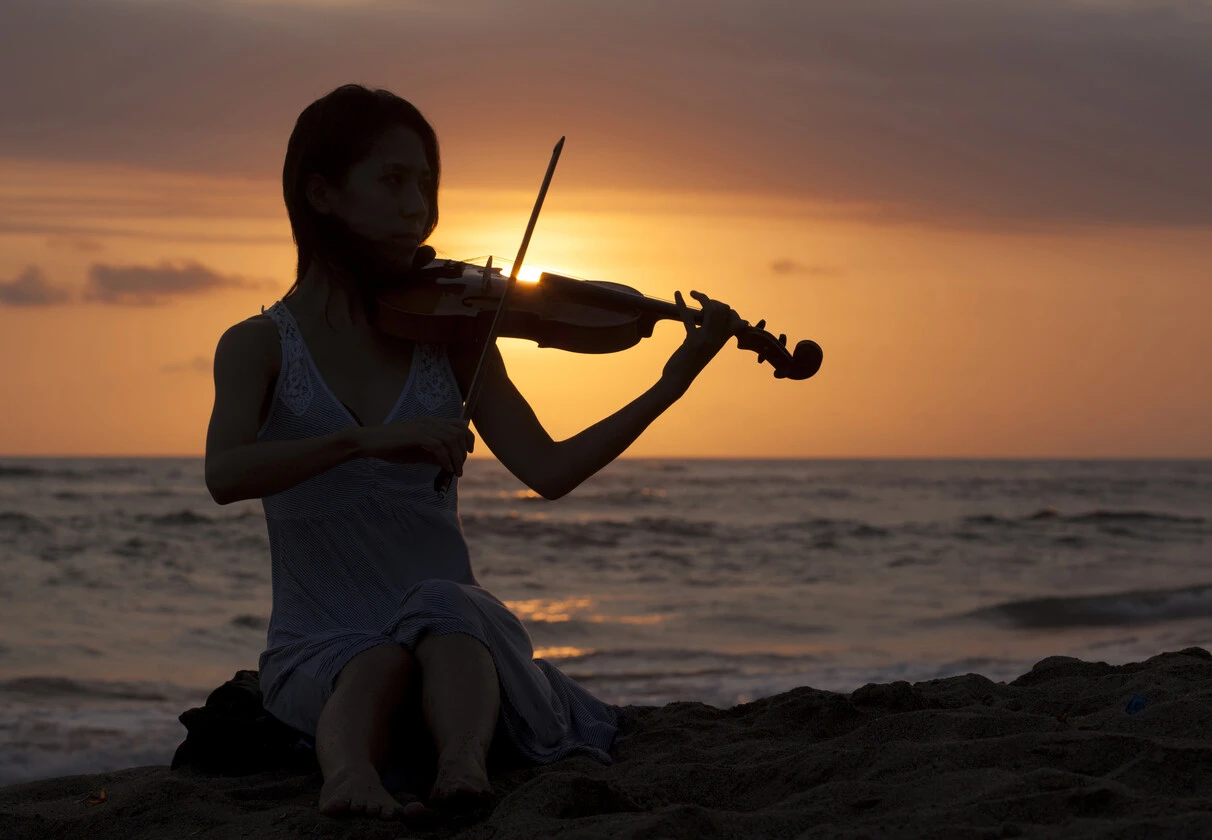 Musician with violin on a beach