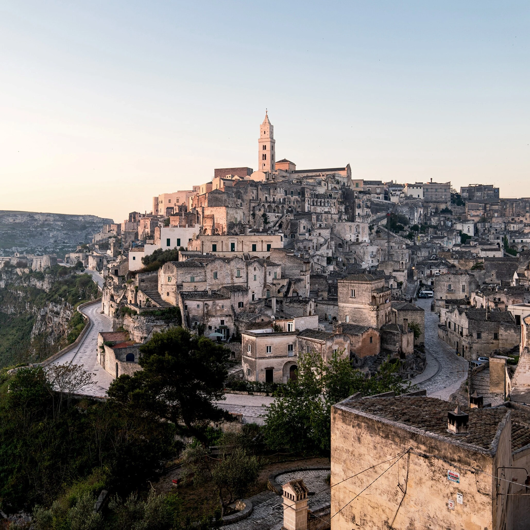  Maisons en pierre de Matera s'étagent sur les falaises des Sassi au lever du soleil, clocher en vue 