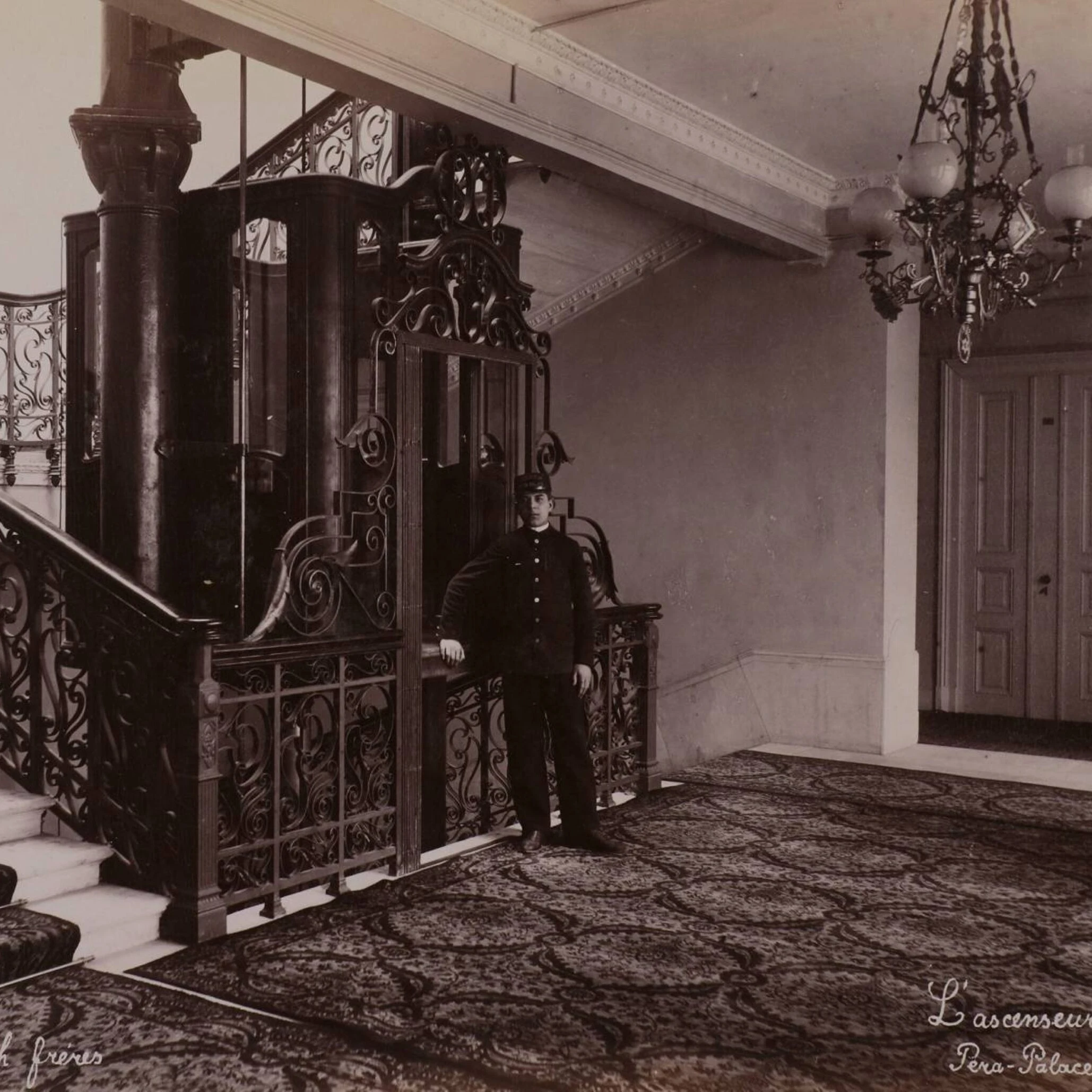 Pera Palace ornate wrought-iron elevator with uniformed attendant standing in historic hotel lobby 