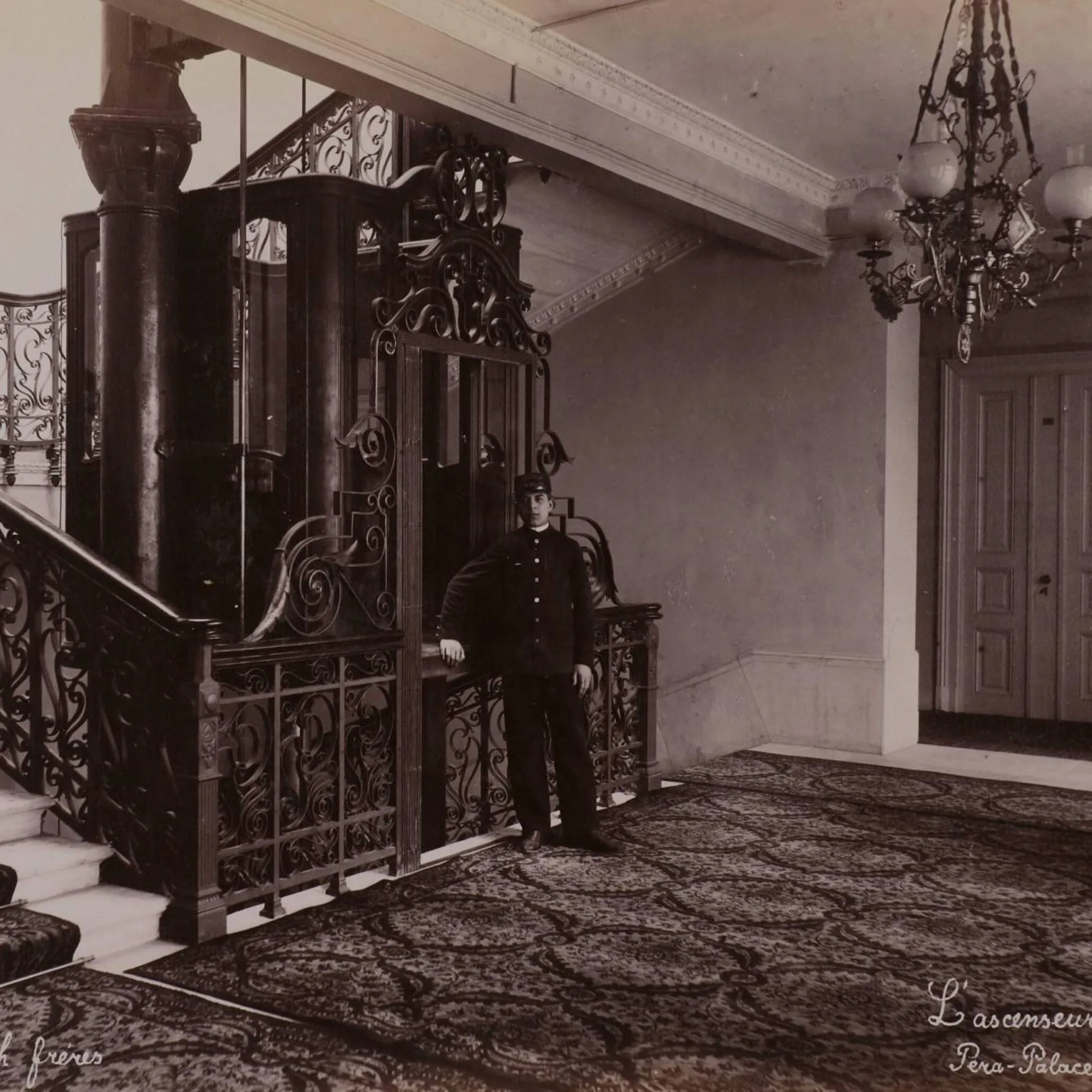 Pera Palace ornate wrought-iron elevator with uniformed attendant standing in historic hotel lobby
