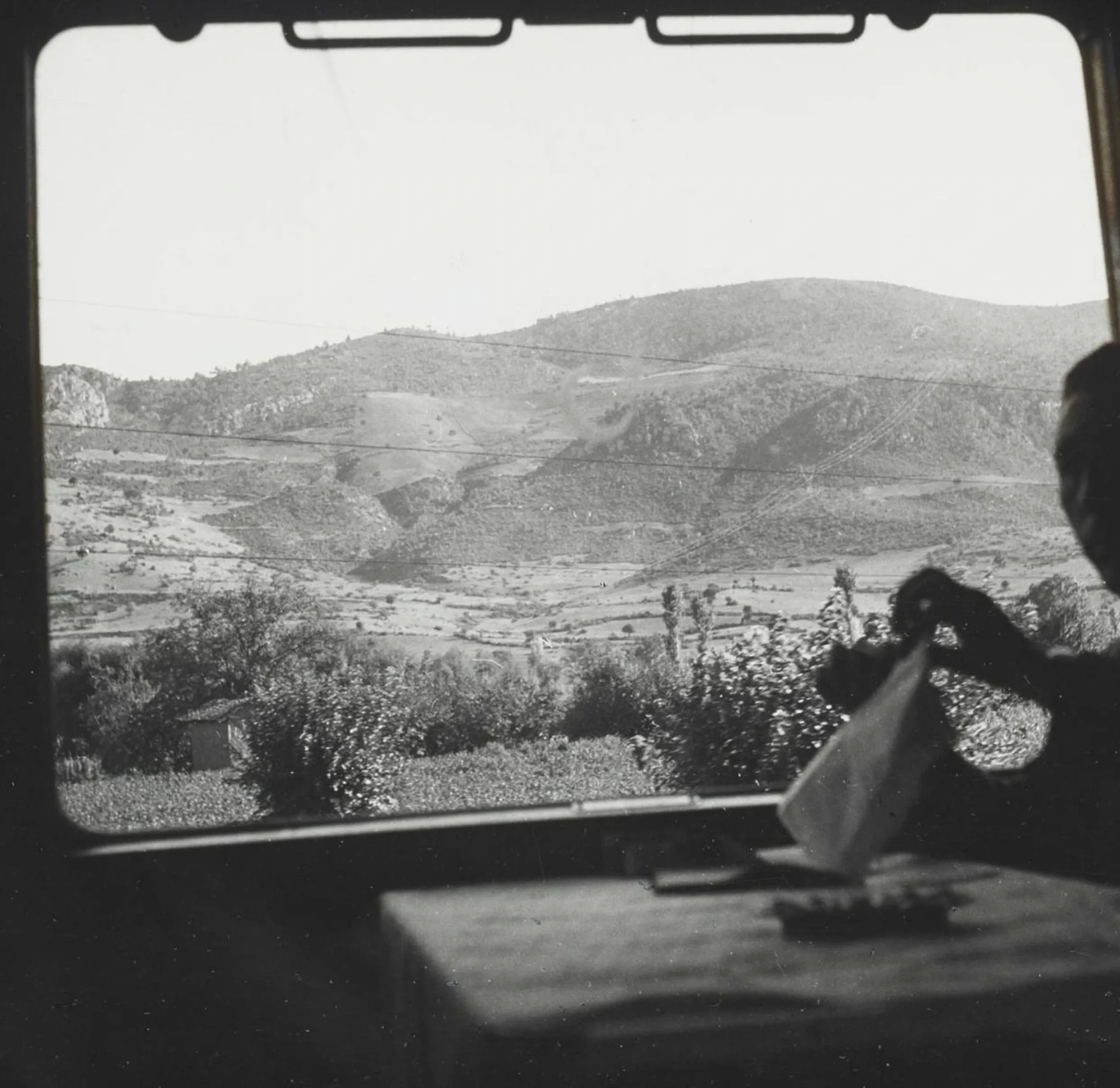 Orient Express passenger unwrapping a napkin at a table, view through carriage window of rolling hills and fields